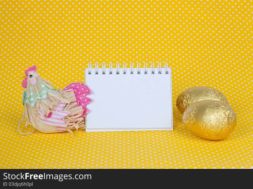 Blank notebook with Easter chocolate eggs isolated on a yellow background. Blank notebook with Easter chocolate eggs isolated on a yellow background