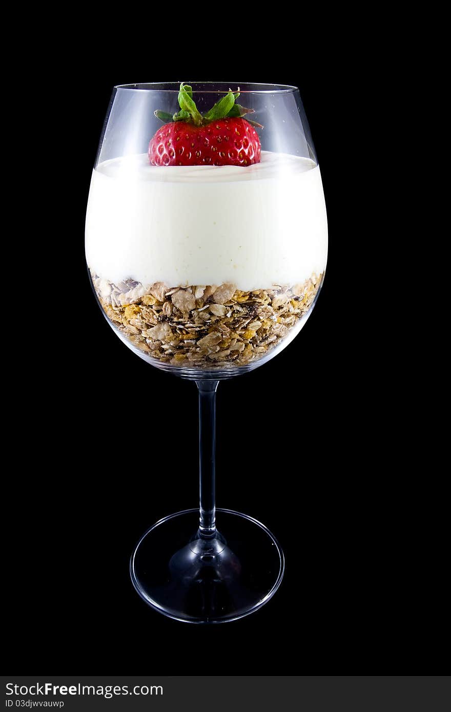 Picture of breakfast, musli and yogurt in a wine glass. With a strawberry on the top