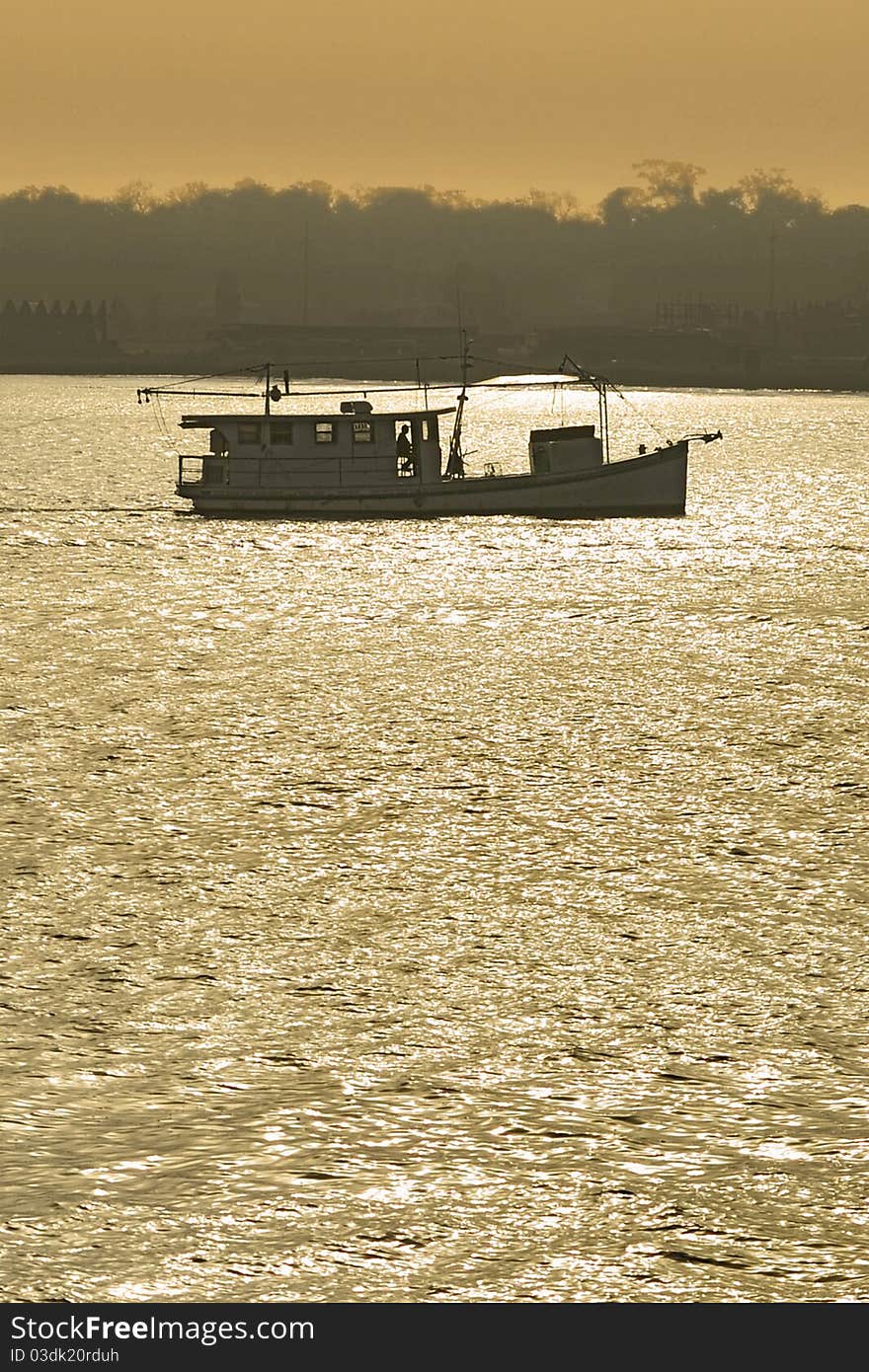 Fishing boat trawling at sunset