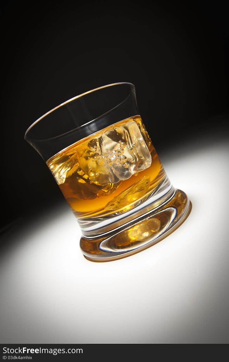 Glass of Whiskey and Ice Under Spot Light.