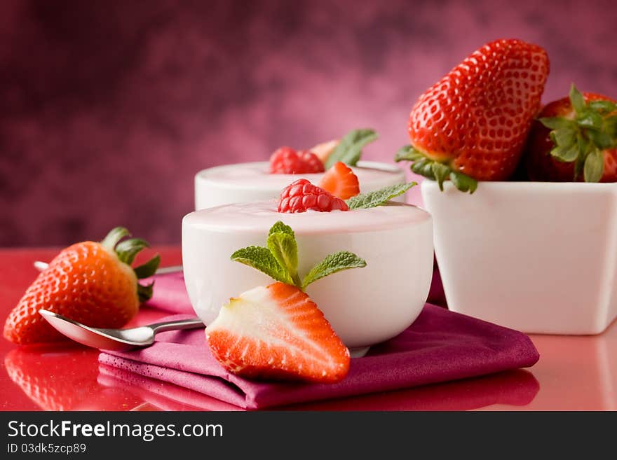Photo of delicious strawberry yogurt on red glass table. Photo of delicious strawberry yogurt on red glass table