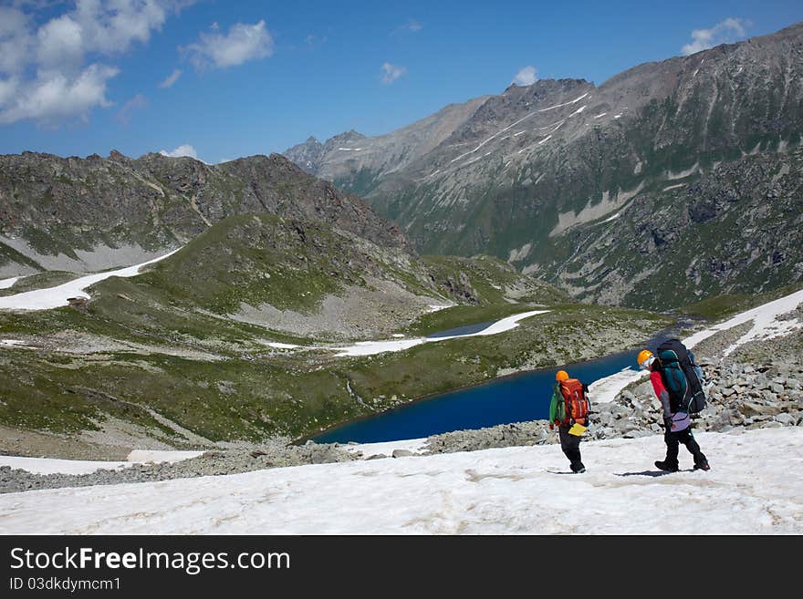 Couple of backpackers in a high mountains walking to the lake