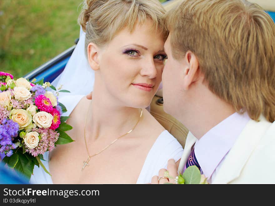 Bride and groom kissing in the car in the field