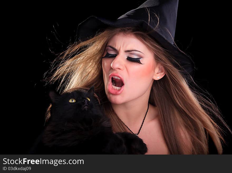 Beautiful girl dressed as a witch holding cat