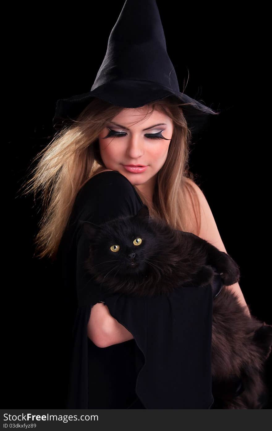 Beautiful girl dressed as a witch holding cat