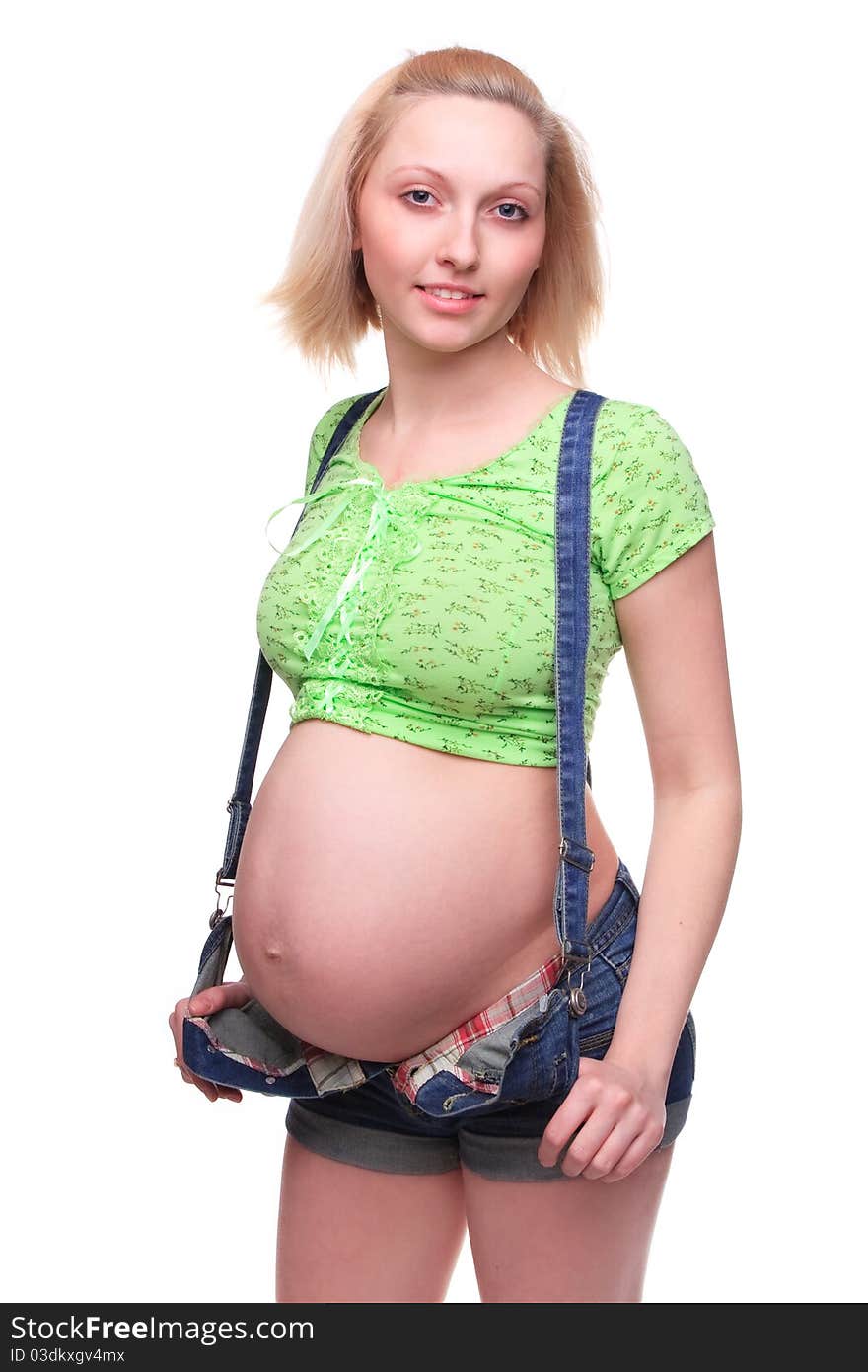 Young pretty pregnant woman posing in jeans overalls