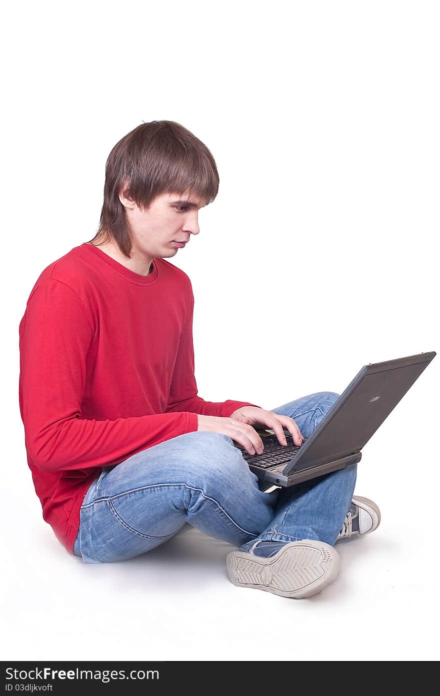 The young man sits on a floor with the laptop. The young man sits on a floor with the laptop