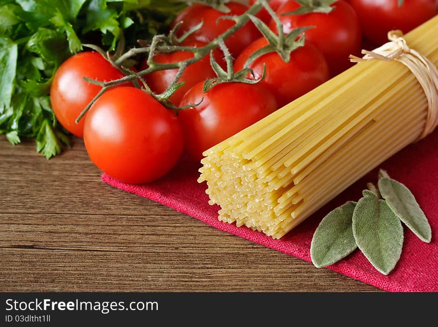 Spaghetti, cherry tomatoes and parsley on a wooden table. Spaghetti, cherry tomatoes and parsley on a wooden table.