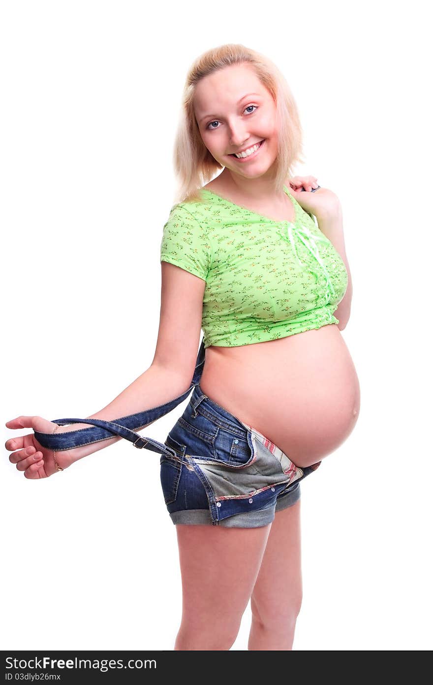 Young pretty pregnant woman posing in jeans overalls