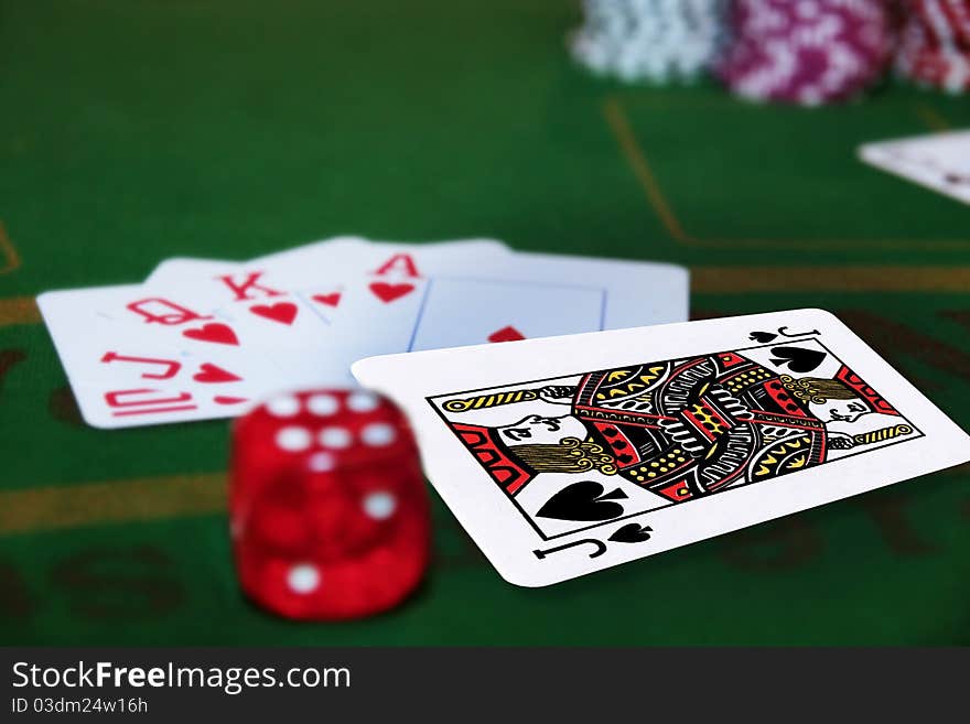 Green casino table with dice and a hand of a royal flush in a poker game and the jack of spades in the pack. Green casino table with dice and a hand of a royal flush in a poker game and the jack of spades in the pack