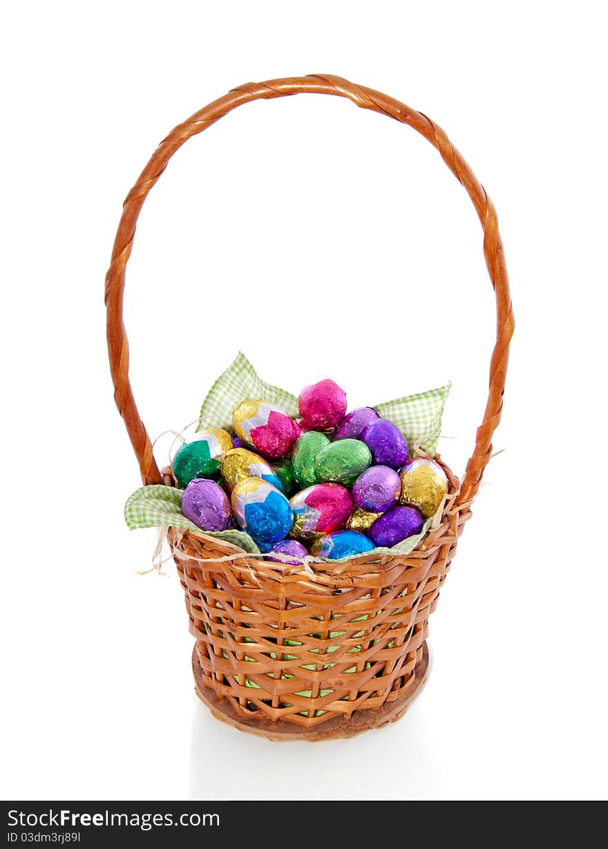 Colorful easter eggs in a wicker brown basket isolated on white background