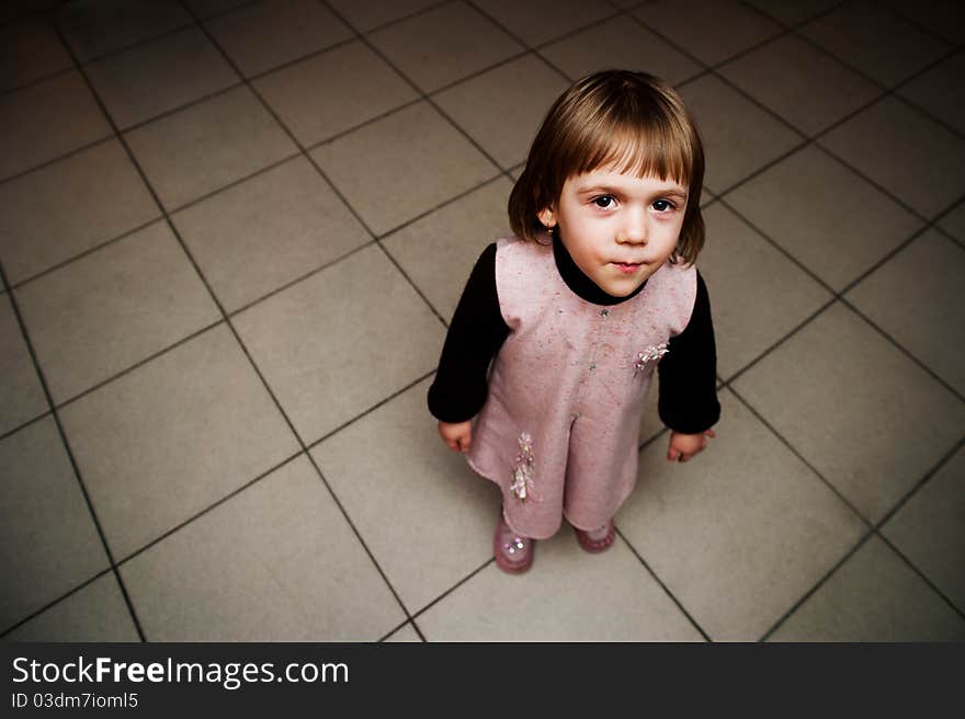 The little girl smiling with interest is looking up. The little girl smiling with interest is looking up