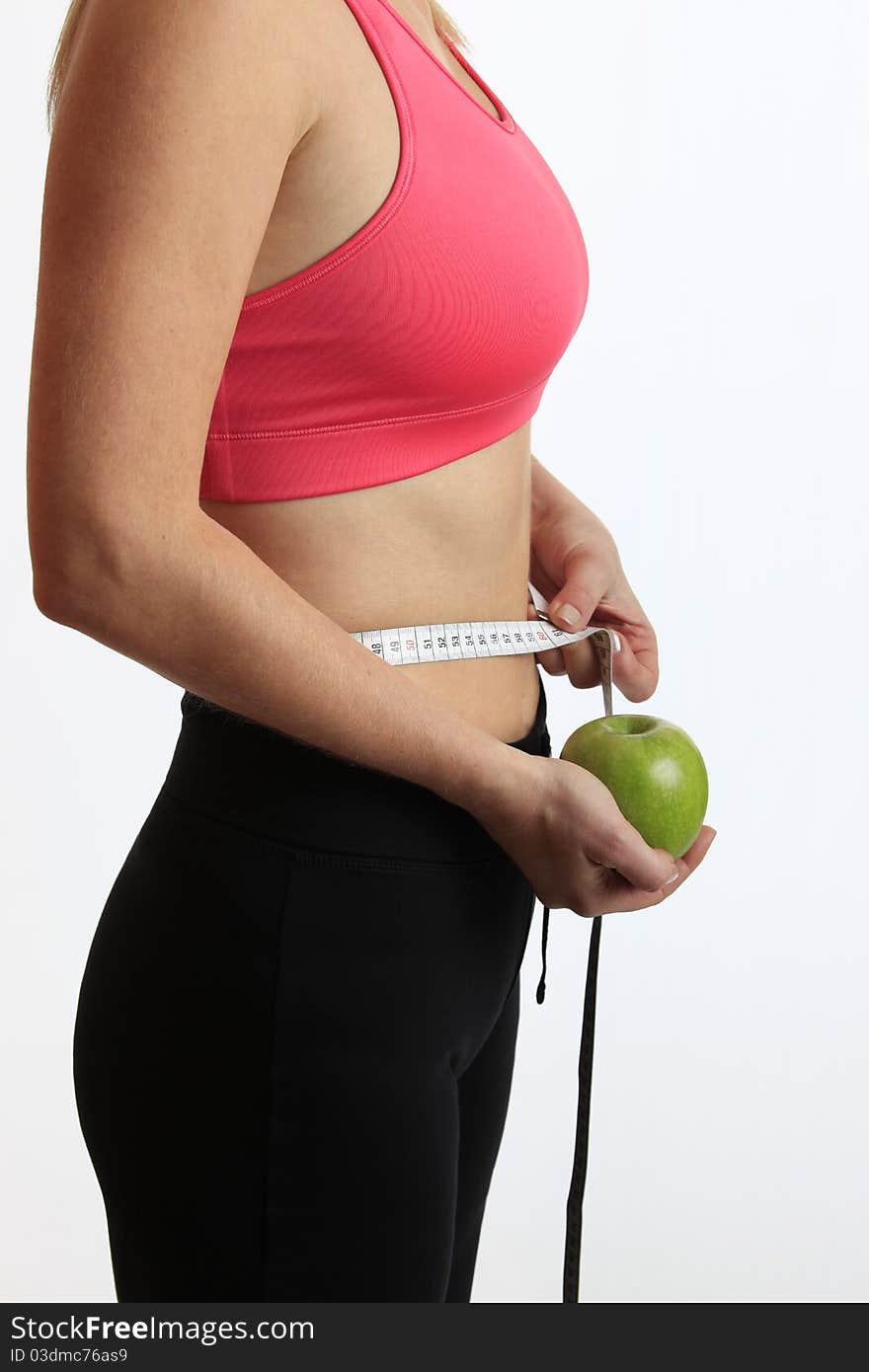 Active woman with green apple and measure tape