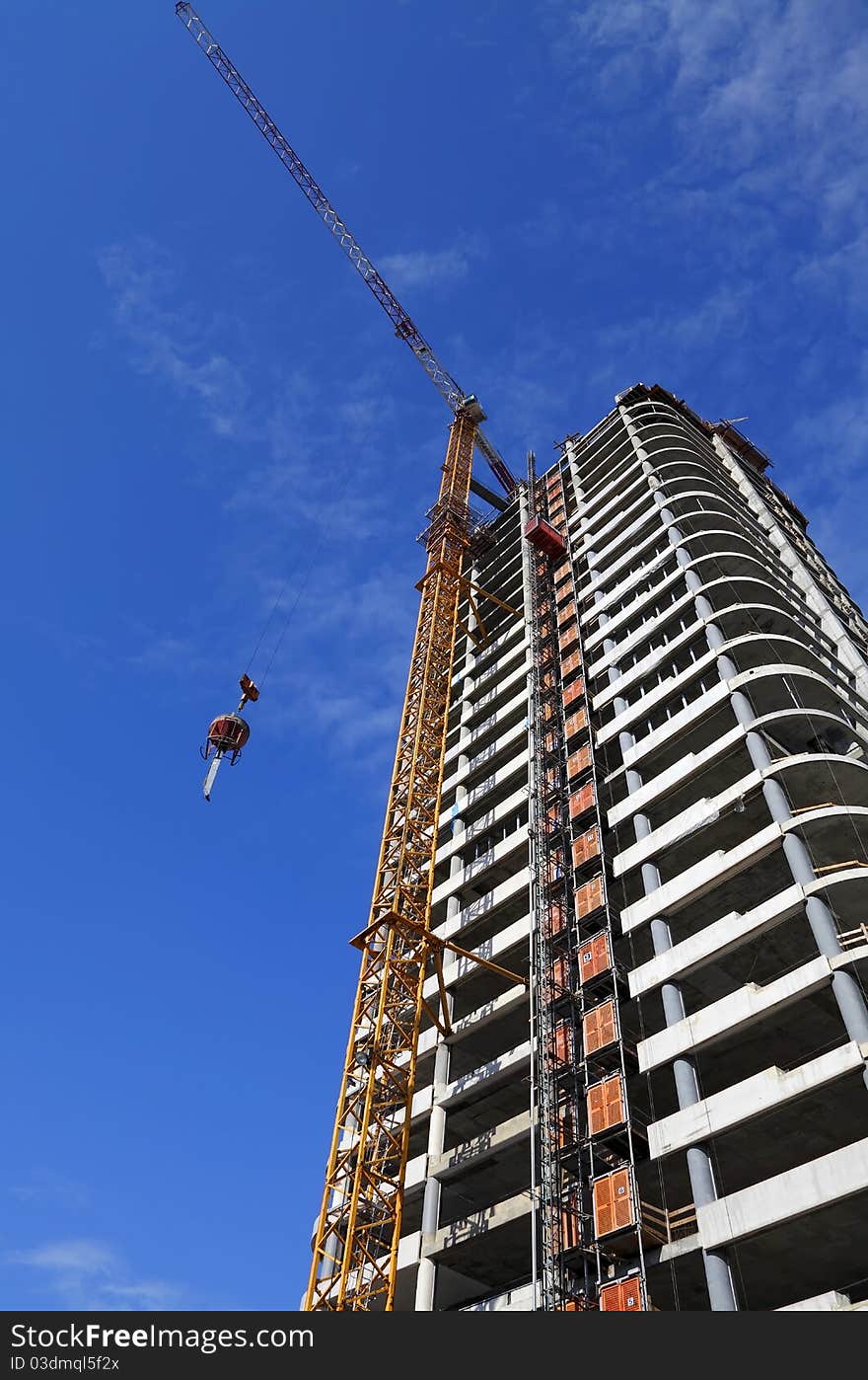 Fragment of a white modern building and the building crane on the blue sky background. Fragment of a white modern building and the building crane on the blue sky background