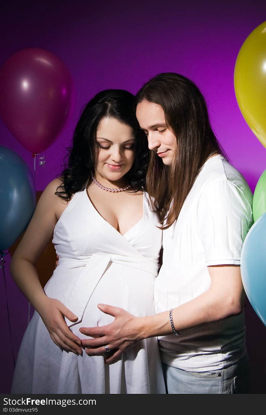 Happy pregnant couple posing in studio