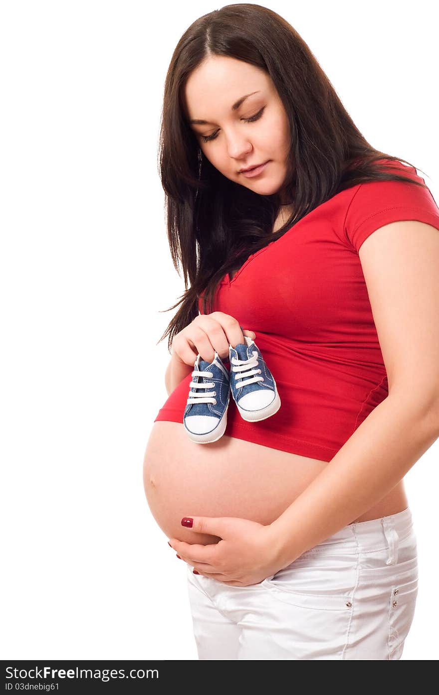 A pregnant woman holding baby shoes