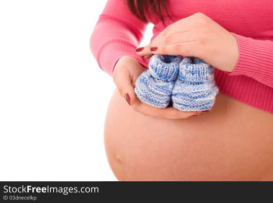 A pregnant woman holding baby shoes