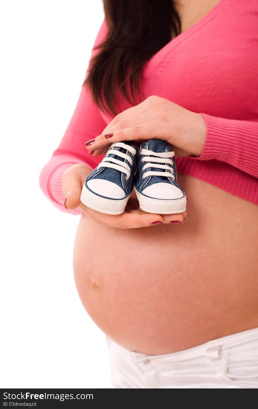 A pregnant woman holding baby shoes