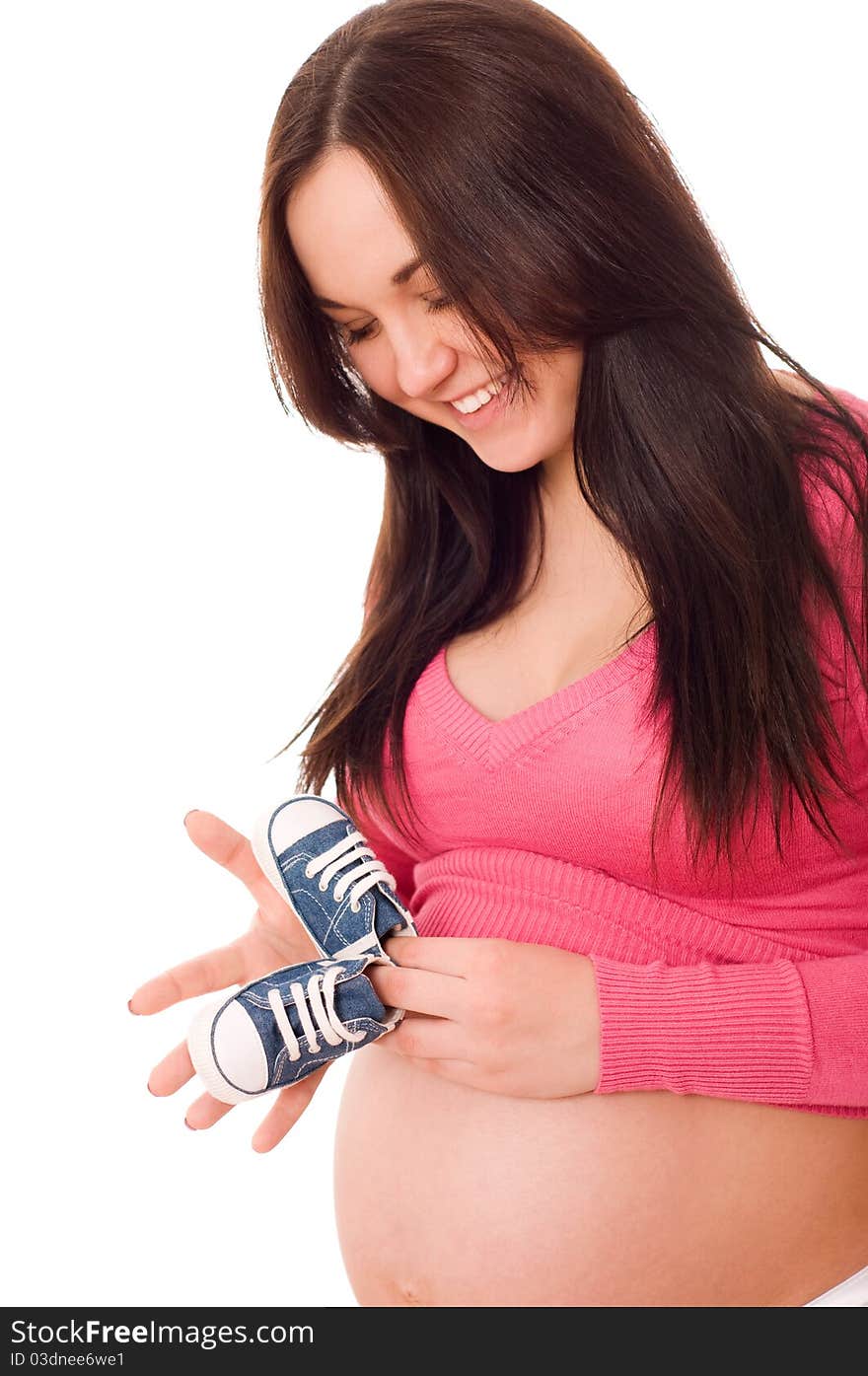 A pregnant woman holding baby shoes