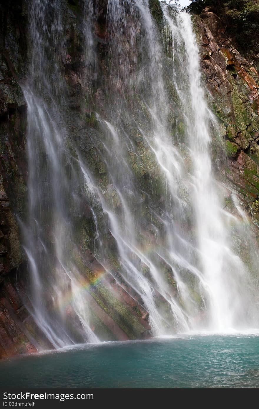 Water running at an angle down Maruo waterfall in Kirishima, Kagoshima, Japan. A small rainbow can be seen in the bottom left. Water running at an angle down Maruo waterfall in Kirishima, Kagoshima, Japan. A small rainbow can be seen in the bottom left.