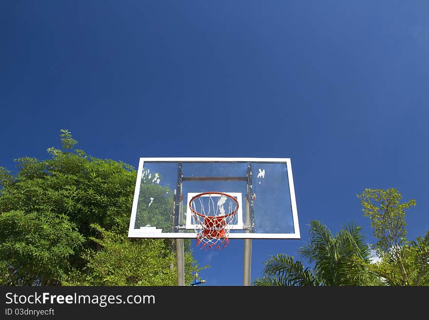 An old basketball hoop and net against a brilliant deep blue sky.