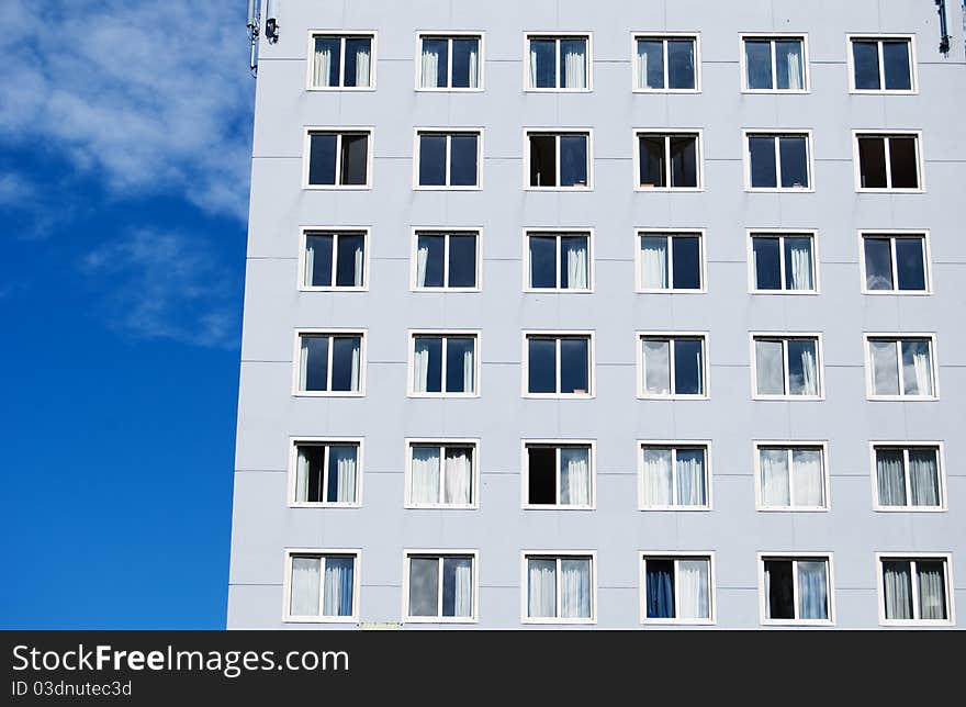 Grey building with big windows against blue sky