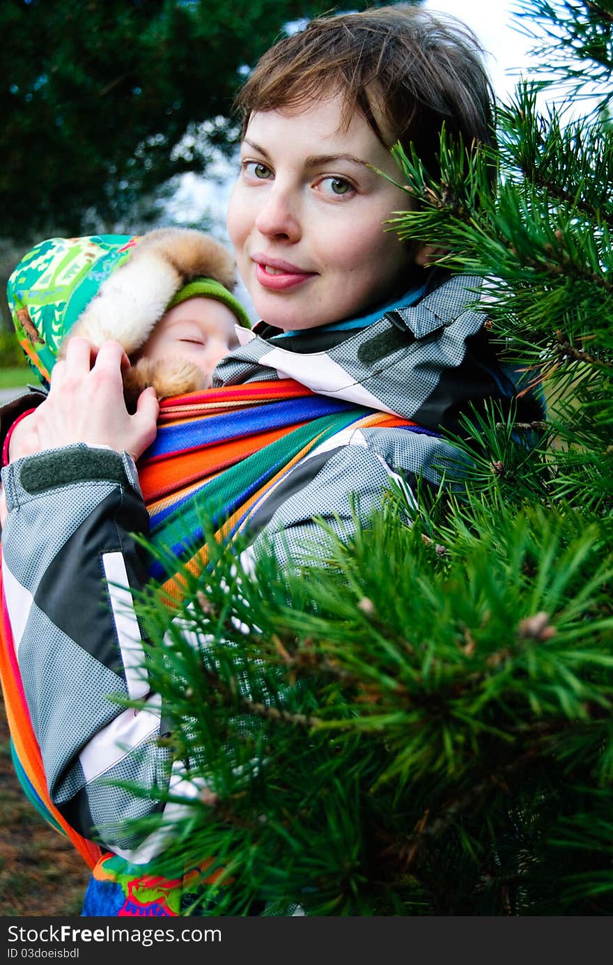 Young mother with her little boy sleeping in baby sling outdoor. Young mother with her little boy sleeping in baby sling outdoor