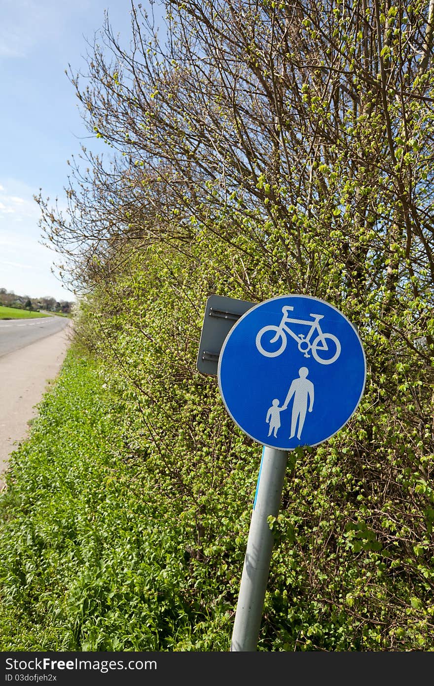 Hedgerow sign indicating a combined cycle and pedestrian footpath beside a country lane. Hedgerow sign indicating a combined cycle and pedestrian footpath beside a country lane.