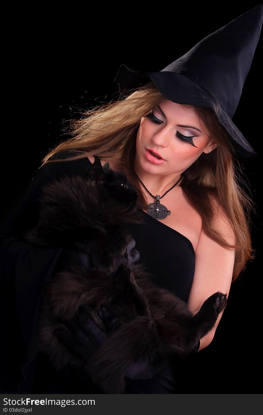 Beautiful girl dressed as a witch holding cat