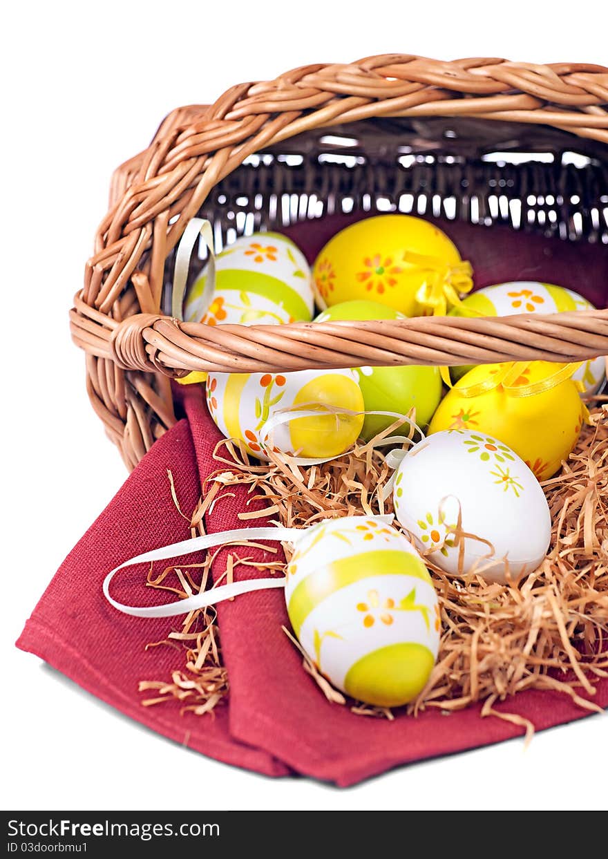 Decorated Easter wicker basket with colorful eggs on red wine napkin