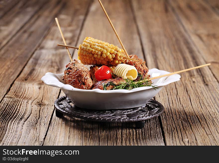 Minced meat kebabs on wooden skewers and roasted sweetcorn