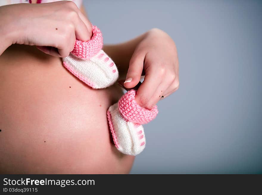 Pregnant woman holding a pair of pink baby booties