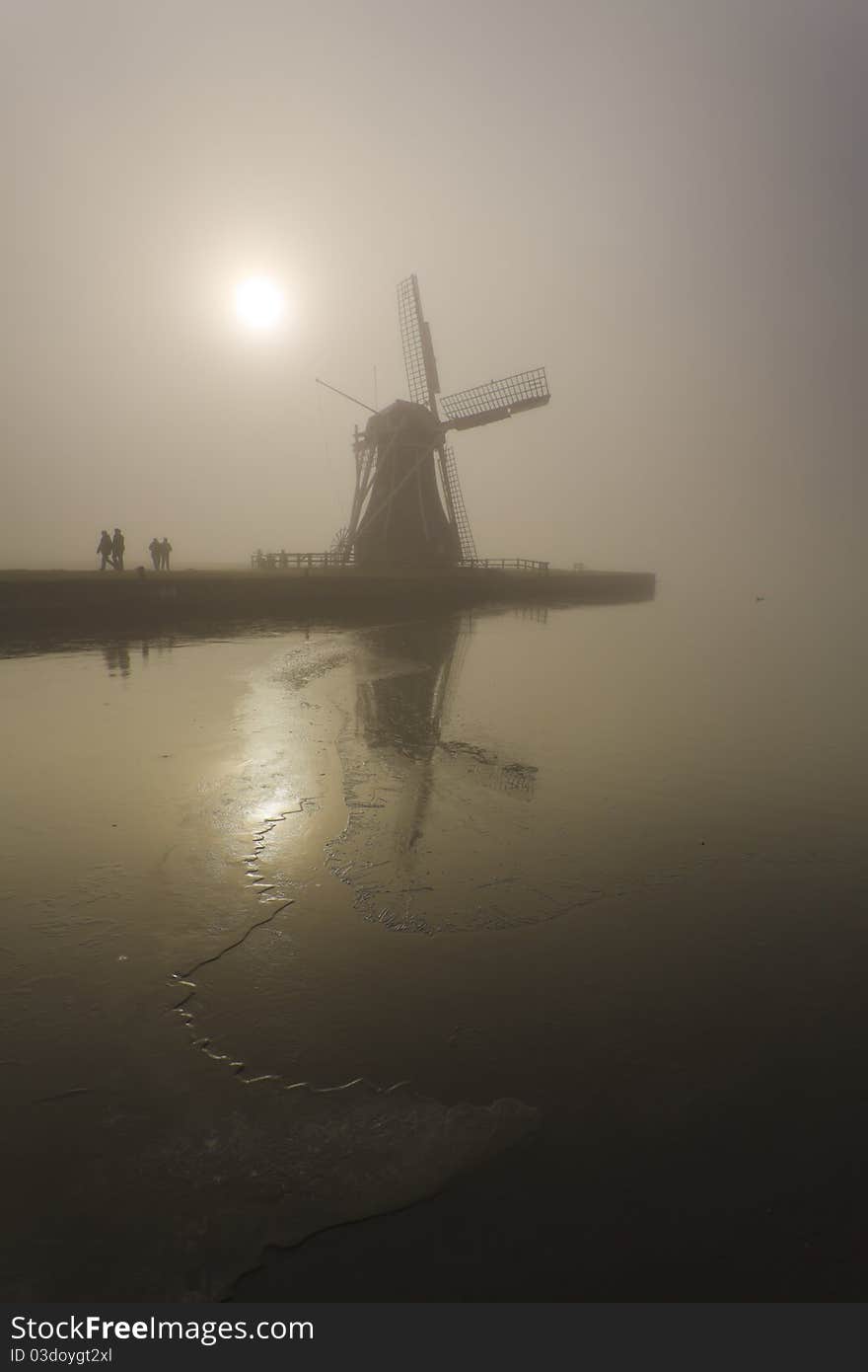 Dutch mill with hikers in the foreground in a foggy environment. Dutch mill with hikers in the foreground in a foggy environment