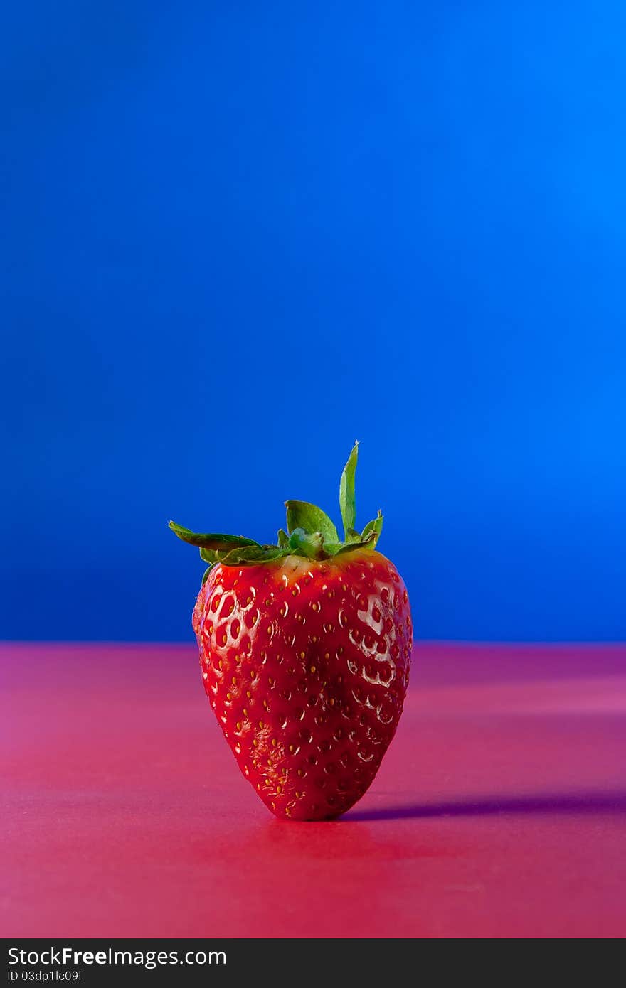 A strawberry on blue background isolated