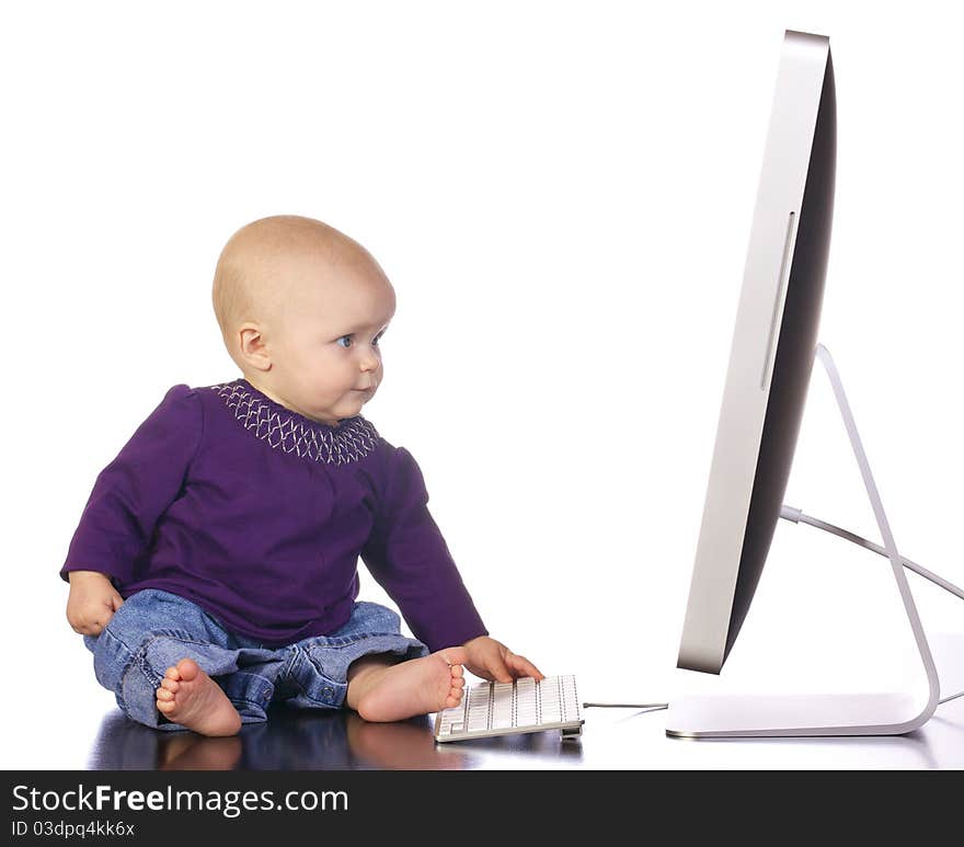 Infant baby girl sitting up looking and playing with a desktop computer screen and keyboard. Infant baby girl sitting up looking and playing with a desktop computer screen and keyboard.