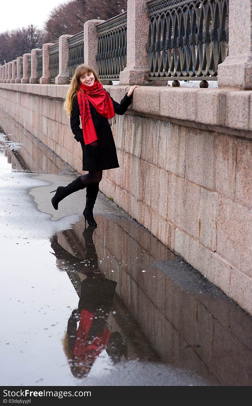 Pretty girl with long hair in red scarf and black coat and her reflection. Pretty girl with long hair in red scarf and black coat and her reflection