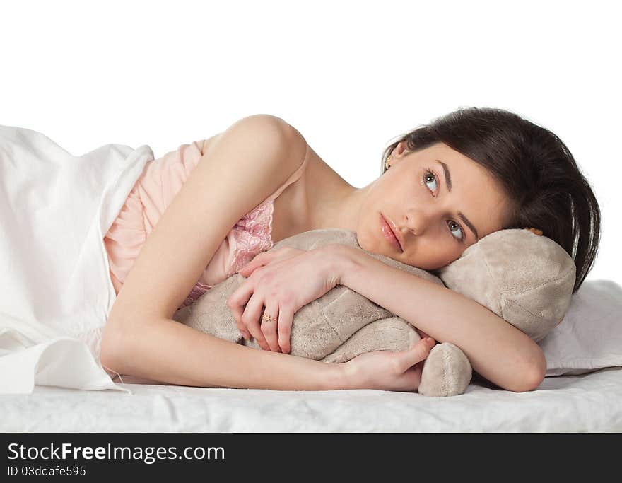 Young women in the bed with toy on a white background