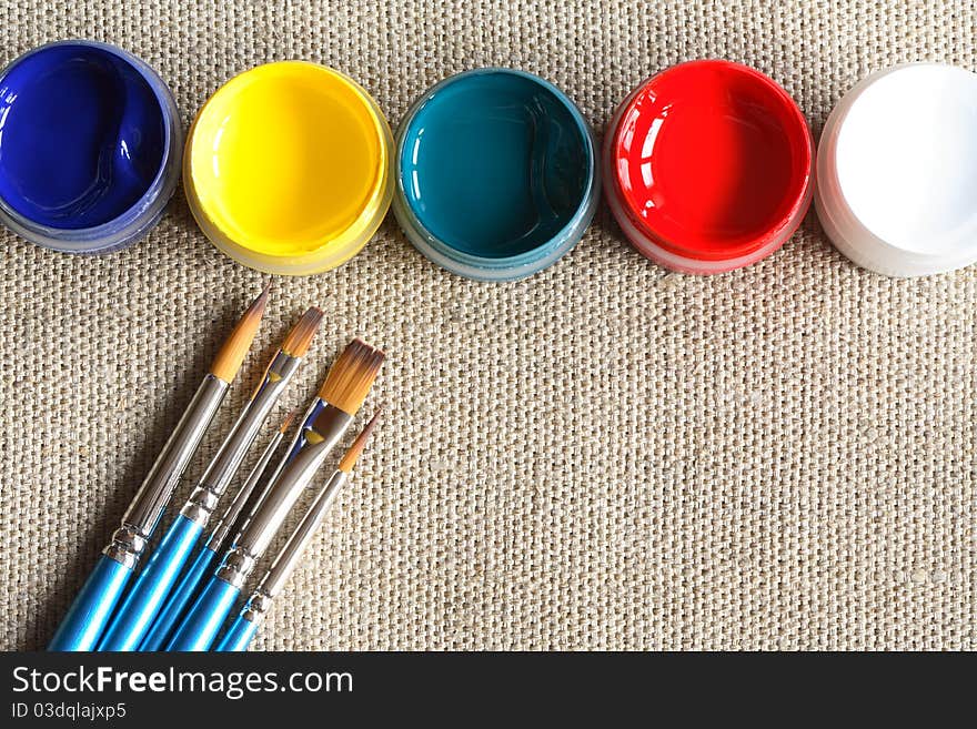 Set of paintbrushes and paint on canvas background. Set of paintbrushes and paint on canvas background