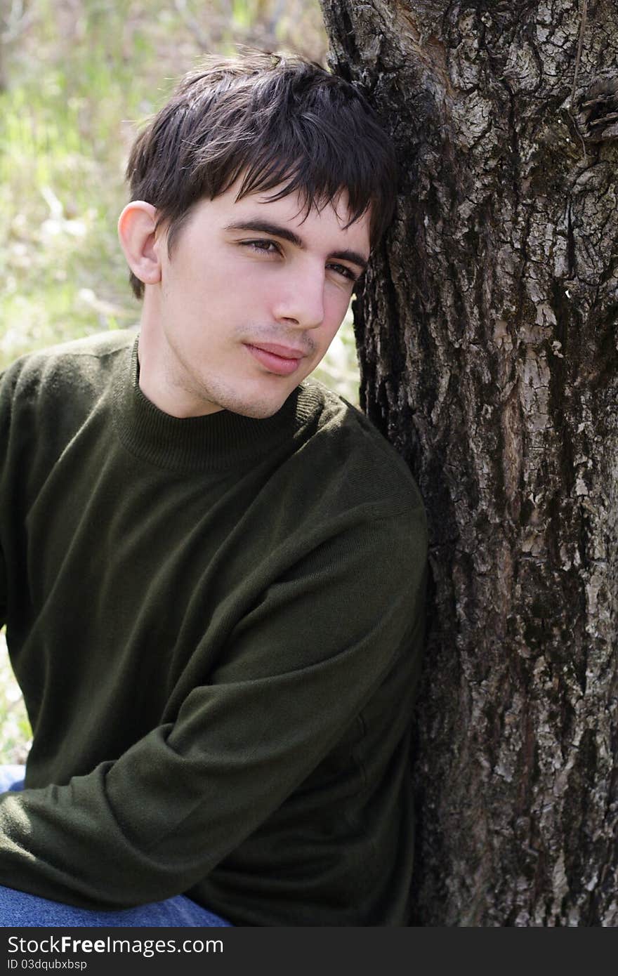 The thoughtful young man sits having leaned against a tree