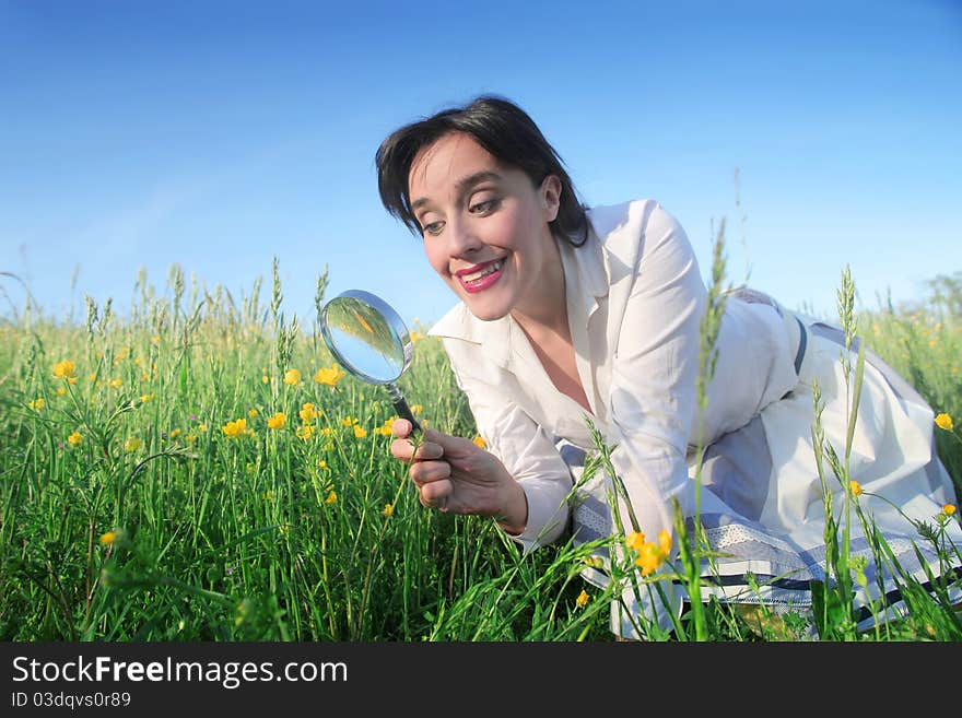 Smiling woman observing flowers through a magnifying glass. Smiling woman observing flowers through a magnifying glass