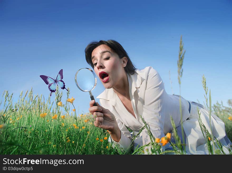 Astonished woman observing a butterfly through a magnifying glass