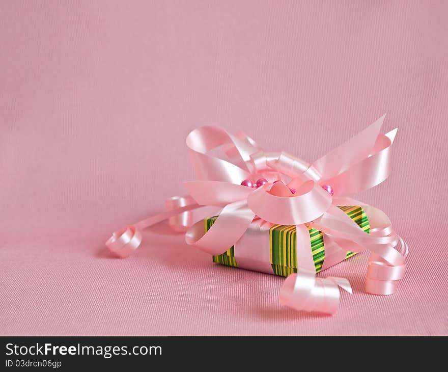 Green gift box with pink ribbon and bow on the pink background. Green gift box with pink ribbon and bow on the pink background.