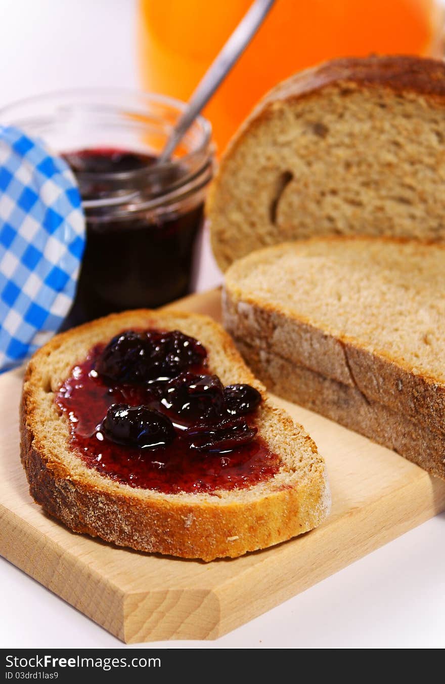 Slices of bread with cherry jam and orange juice in the background