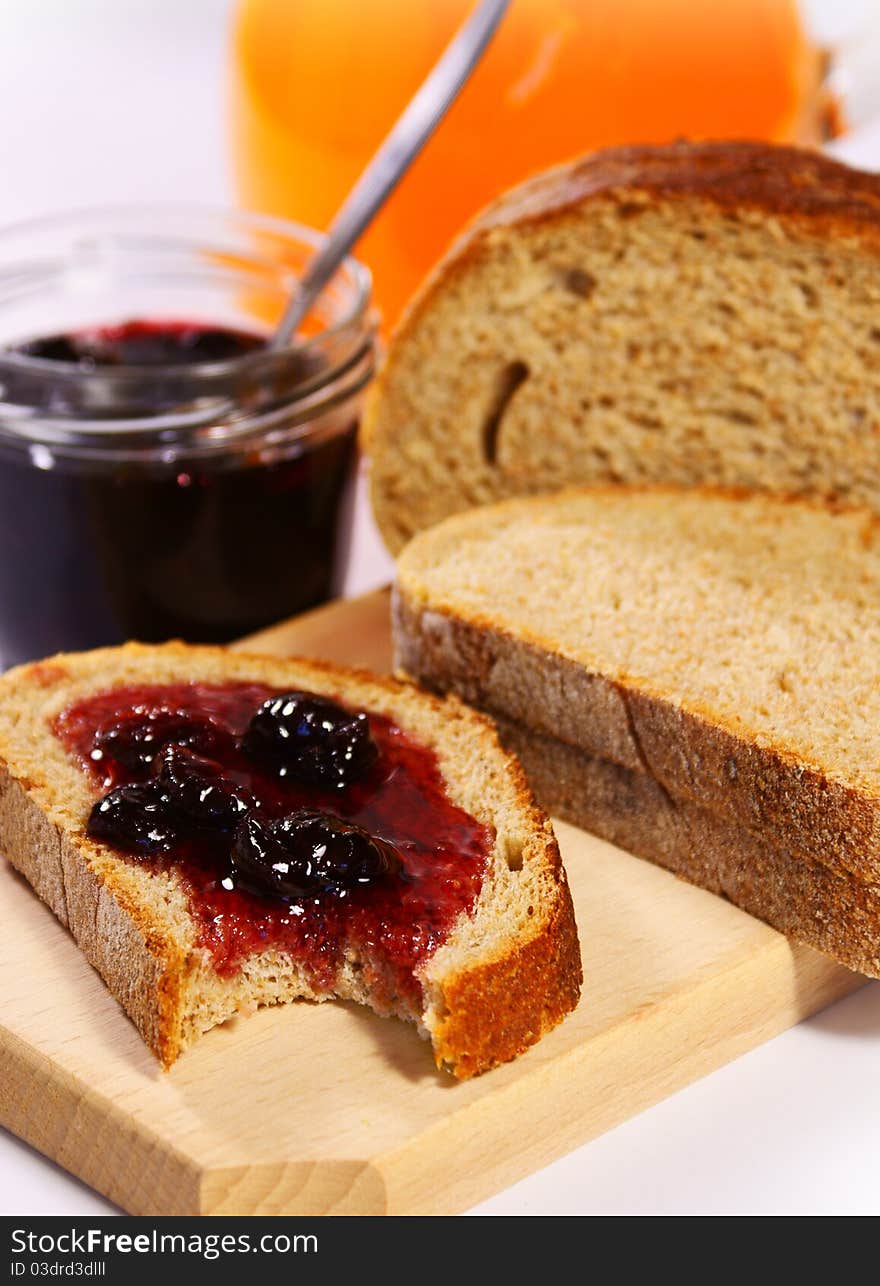 Slices of bread with cherry jam and orange juice in the background