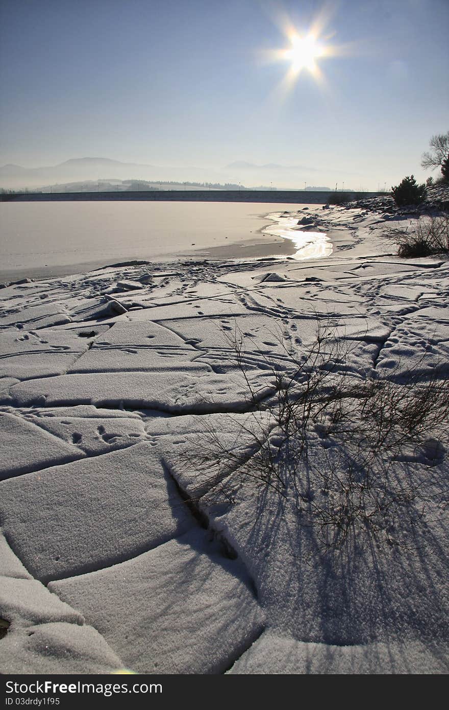 Nort part of Slovakia, by the lake Liptocska Mara in winter season. Cold sun shune over the water. Snow and ice.