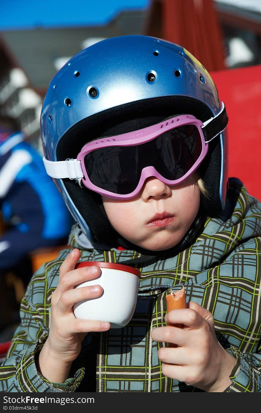 Little girl in helmet and glasses eats and drink