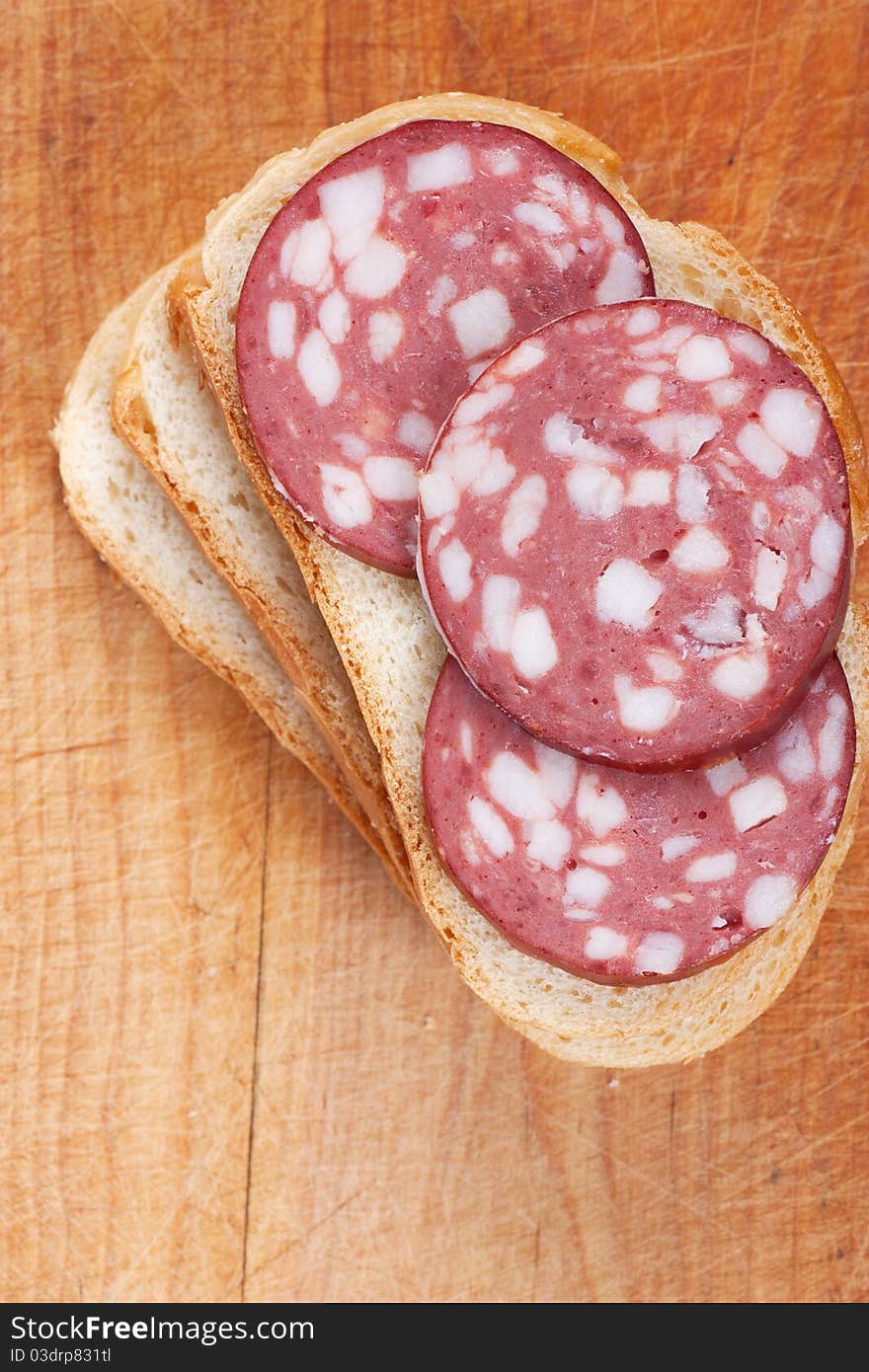 Slices of sausage on a bread on a wood board