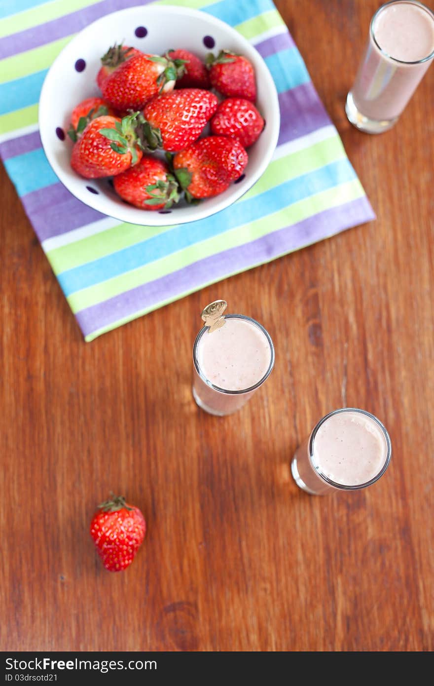 Yogurt cocktail on the wooden table with bowl of strawberries. Yogurt cocktail on the wooden table with bowl of strawberries