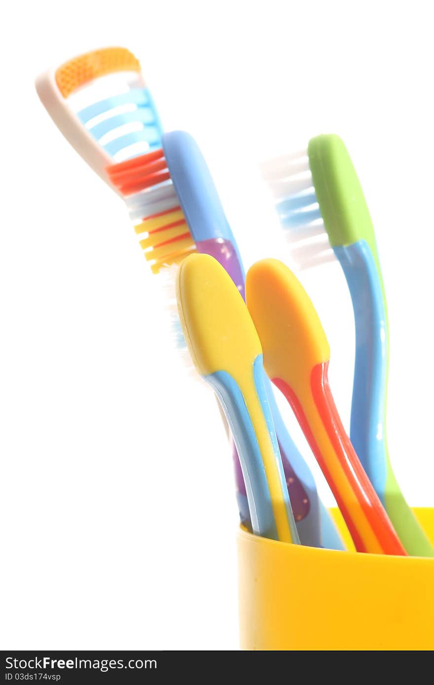 Toothbrushes in a yellow glass