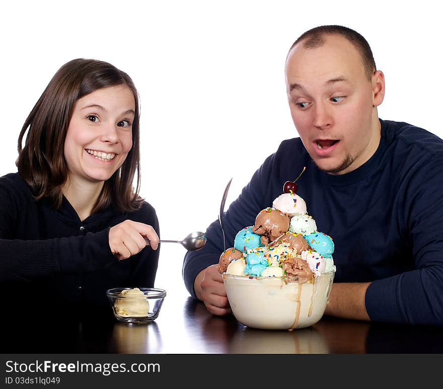 Young man cautiously watches his wife try to steal a spoon full of his giant bowl of multi-flavored scoops of ice cream. Young man cautiously watches his wife try to steal a spoon full of his giant bowl of multi-flavored scoops of ice cream.